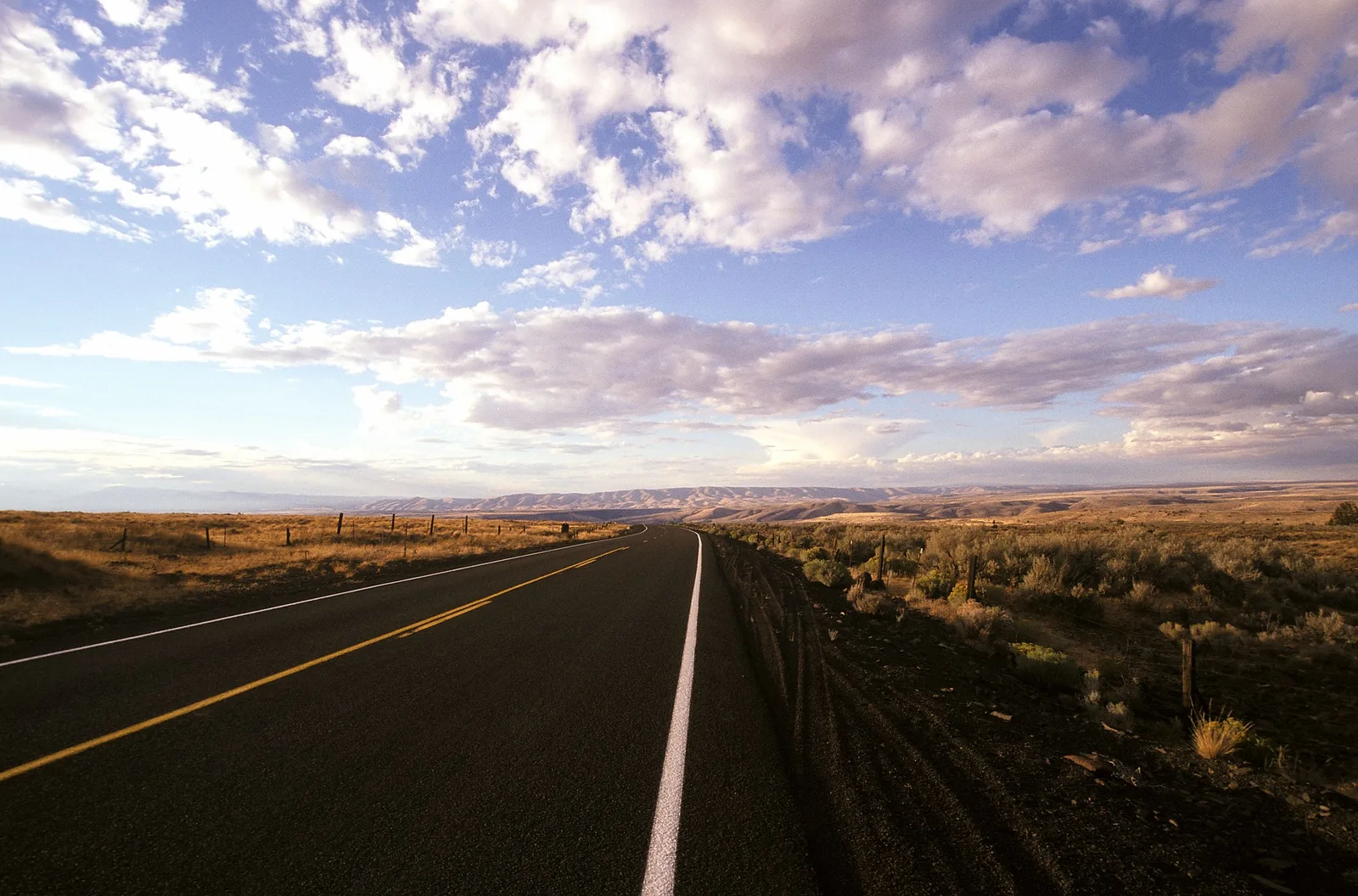 Open two-lane road stretching through Oregon high desert at dusk