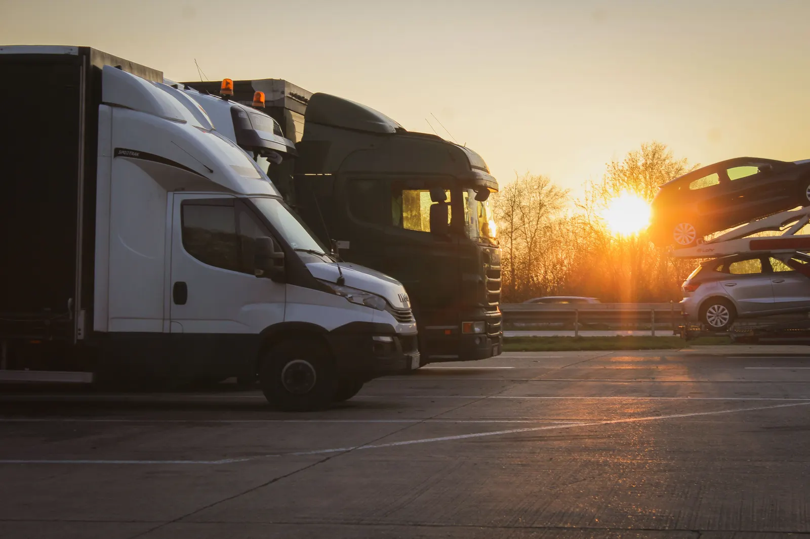 A row of trucks parked at sunset in an open highway lot