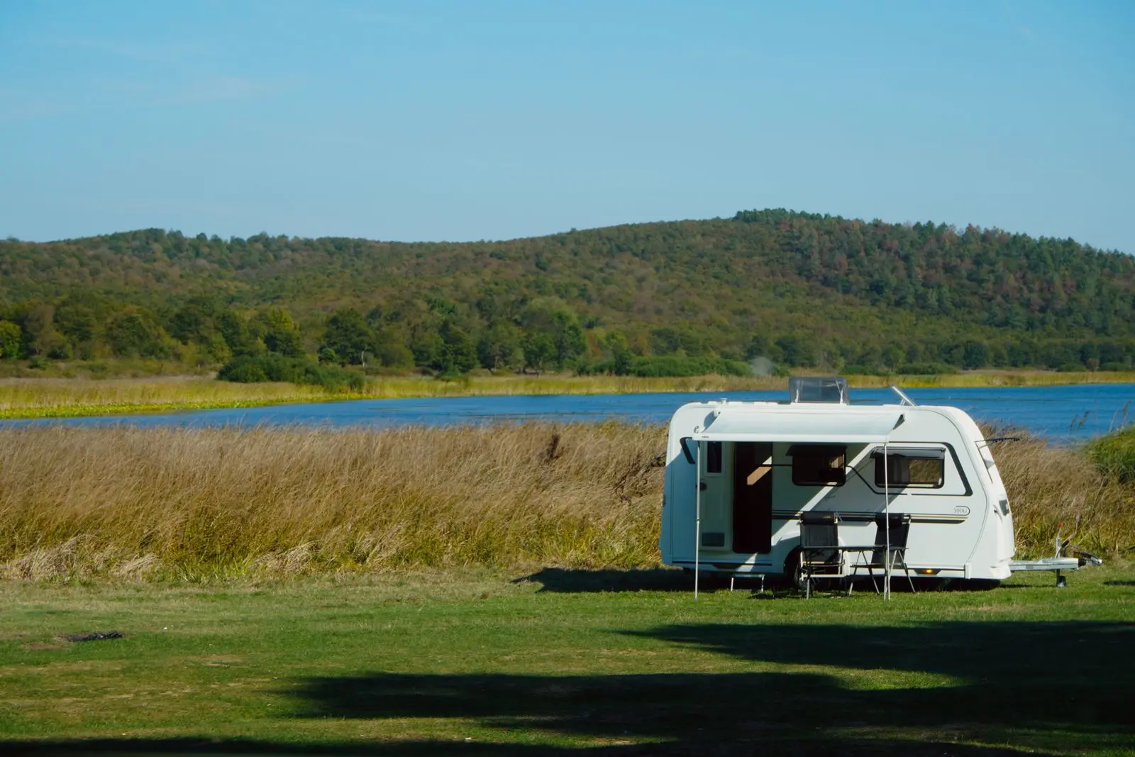 Travel trailer parked at a lakeside campsite in green forest
