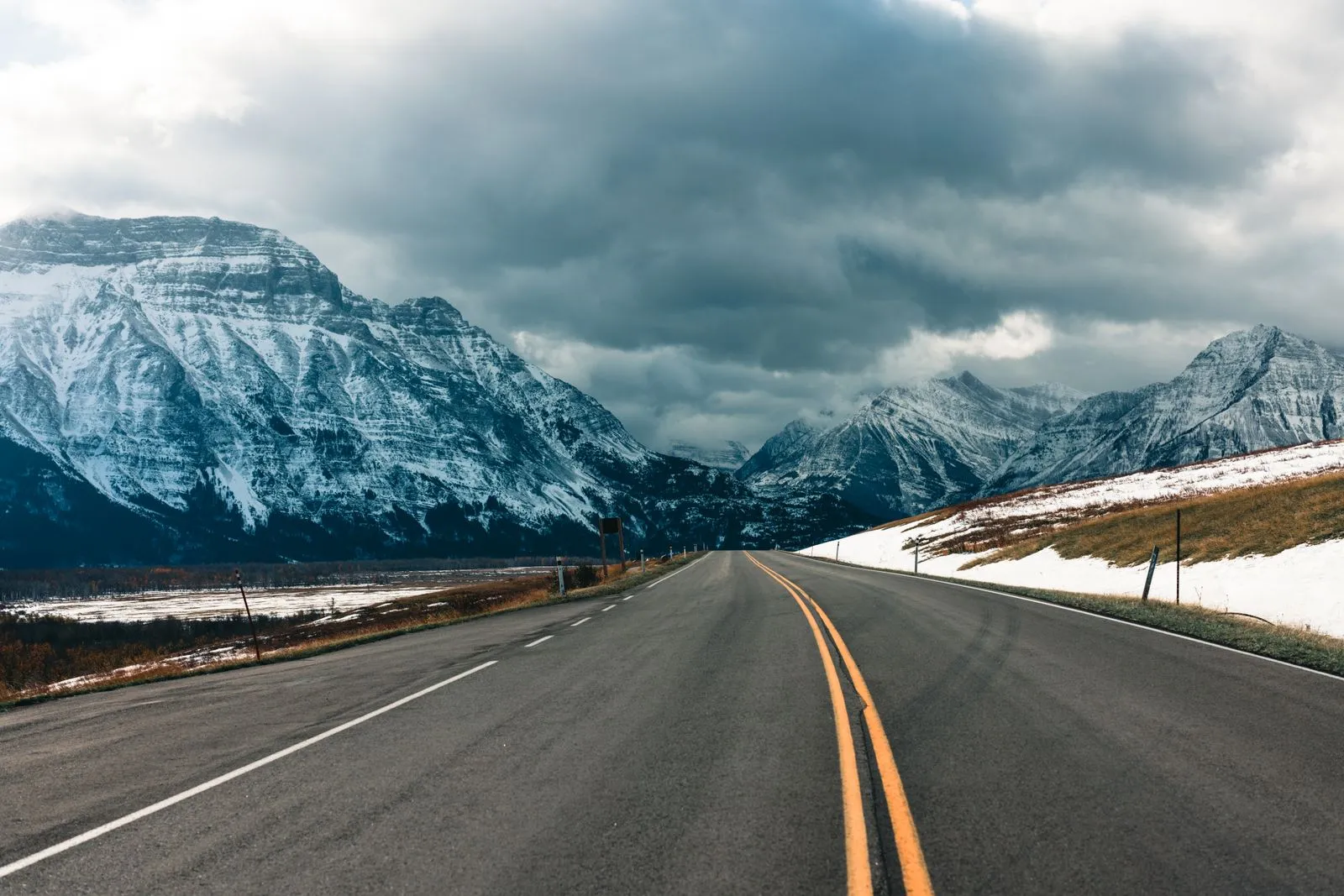 A highway curves through snow-capped mountains in the Glacier and Waterton area