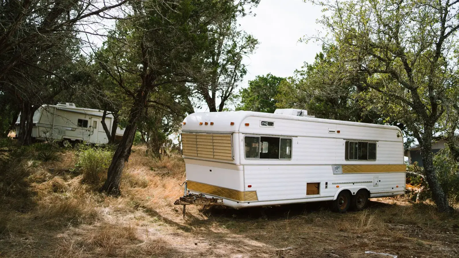 A travel trailer parked at a wooded campsite