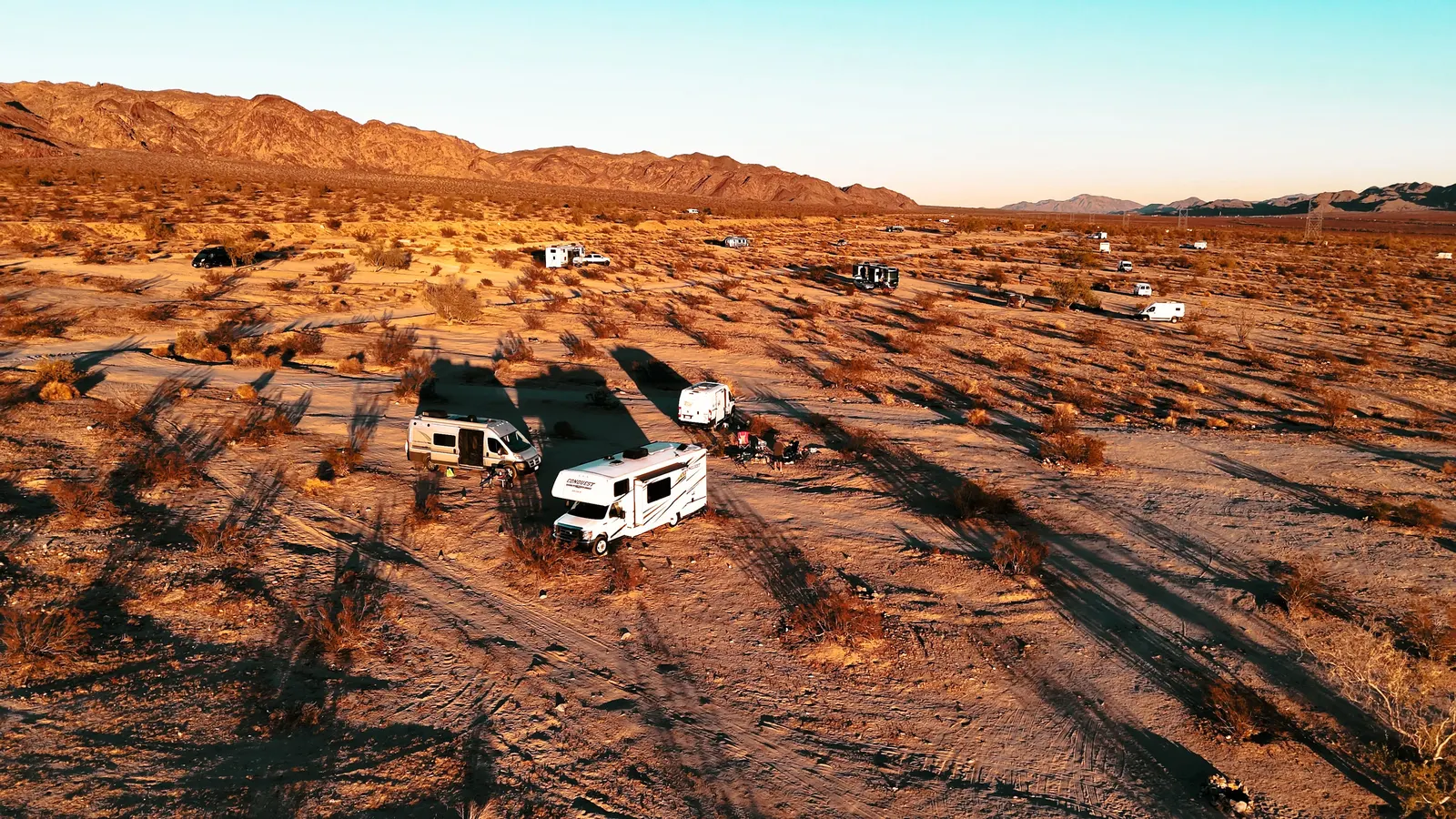 Aerial view of RVs camped across open desert at sunset