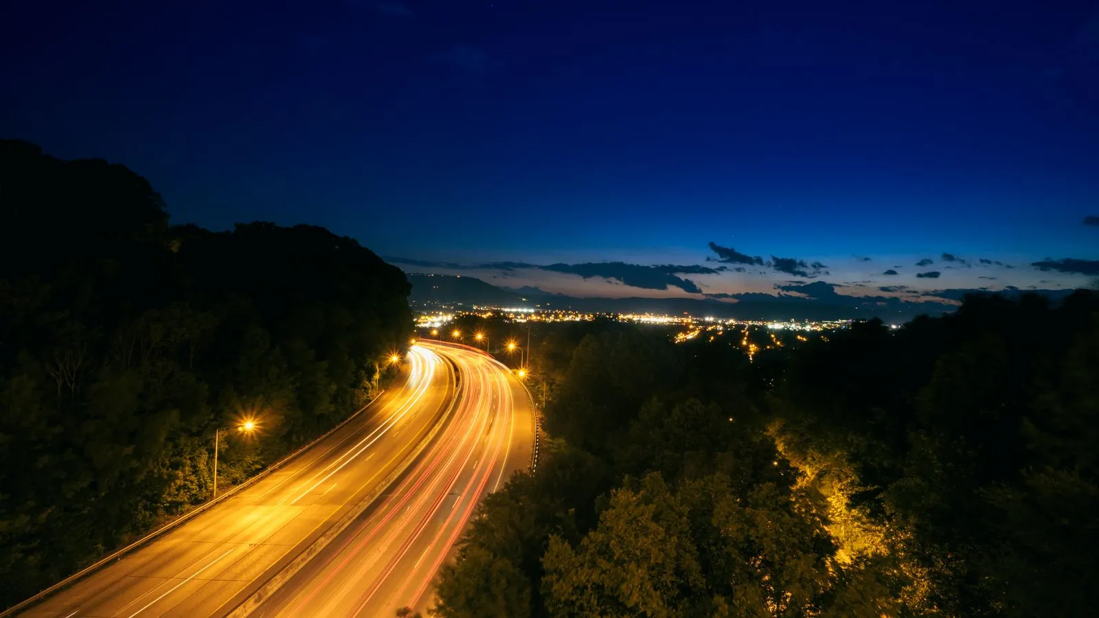 Long-exposure light trails from vehicles on an interstate at night